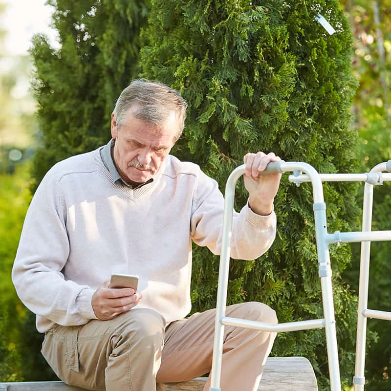 Ältere Person schaut sitzend auf sein Handy